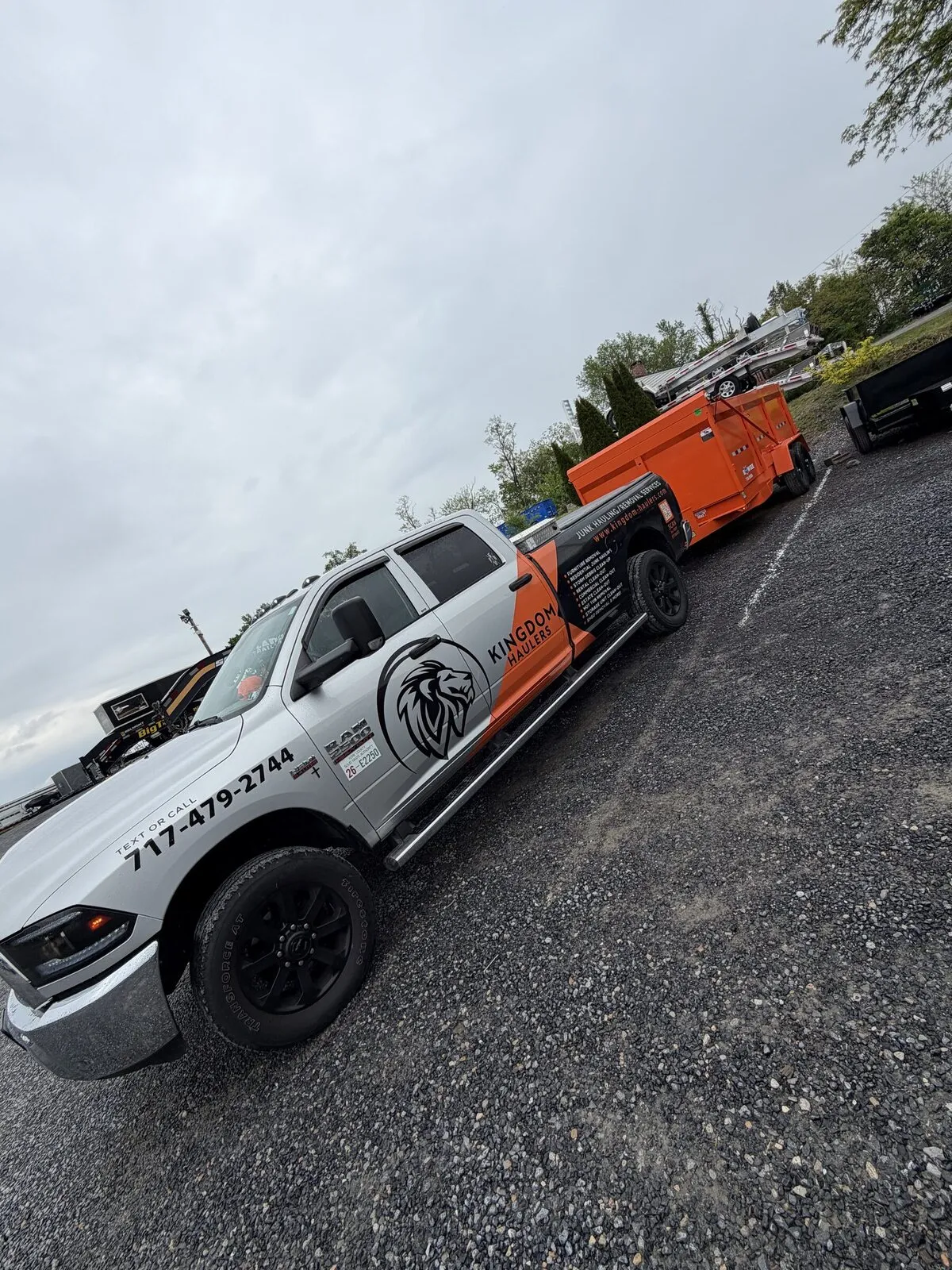 Kingdom Haulers wrapped pickup towing an orange dump-trailer dumpster